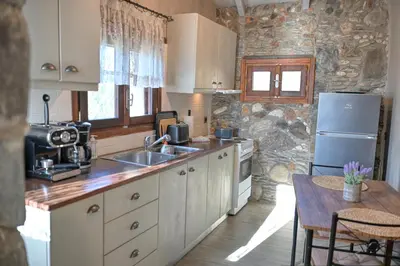 a kitchen with a sink and a refrigerator and a table at Velanos Villas in Kefálion