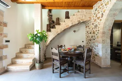 a dining room with a stone staircase and a table and chairs at Villa Eliomylos in Souda