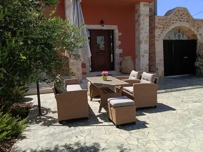 a patio with a table and chairs and an umbrella at Villa Eliomylos in Souda