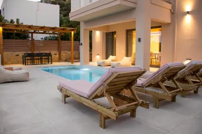 a patio with two lounge chairs and a swimming pool at Armour Eclectic Villa in Afráta