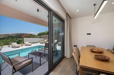 a dining room with a table and a swimming pool at Armour Eclectic Villa in Afráta