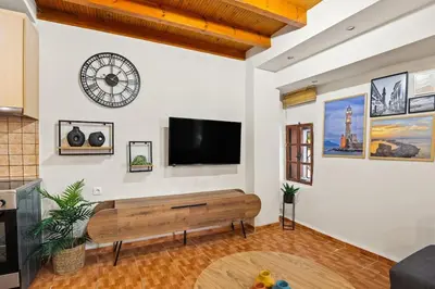 a living room with a bench and a flat screen tv at Rodon maisonette in Chania Town