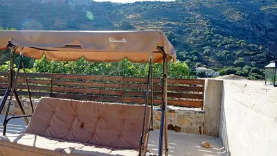a chair under an umbrella on top of a building at Polyraki's Cottage in Chania Town