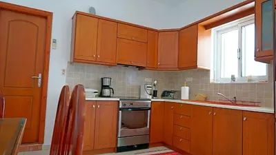 a kitchen with wooden cabinets and a stove and a window at Polyraki's Cottage in Chania Town