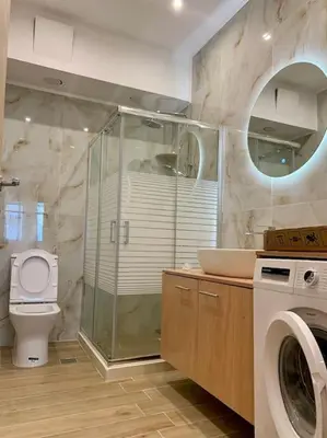 a bathroom with a shower and a toilet and a washing machine at Paleochora Beach Studio (BRAND NEW) in Palaiochóra