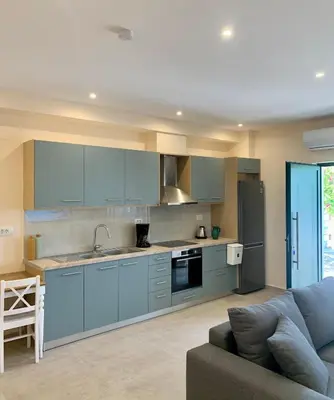 a kitchen with blue cabinets and a couch at Paleochora Beach Studio (BRAND NEW) in Palaiochóra