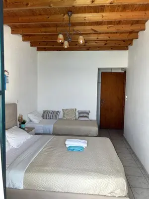 a bedroom with two beds and a wooden ceiling at Notos Rooms in Loutro