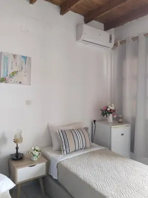 a bedroom with two twin beds and a bed istg at Notos Rooms in Loutro