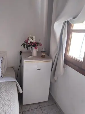 a small white cabinet with a vase of flowers on it at Notos Rooms in Loutro