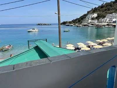a beach with umbrellas and people in the water at Notos Rooms in Loutro