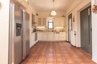 a kitchen with white cabinets and a tiled floor at Marika Seaside Villa in Yialós