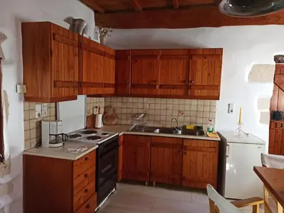 a kitchen with wooden cabinets and a stove top oven at Small traditional house in Douliana