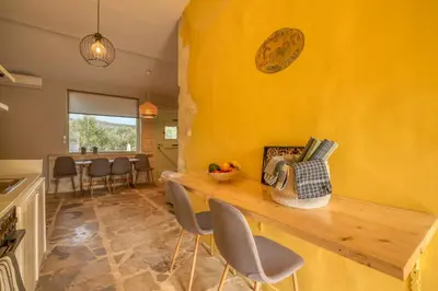 a kitchen with a yellow wall and a table with chairs at Mourelo Home in Gavalochori