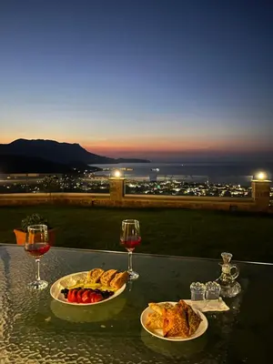 a table with two plates of food and glasses of wine at Korfali Apartments in Kissamos