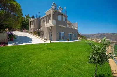 a large house with a green lawn in front of it at Korfali Apartments in Kissamos