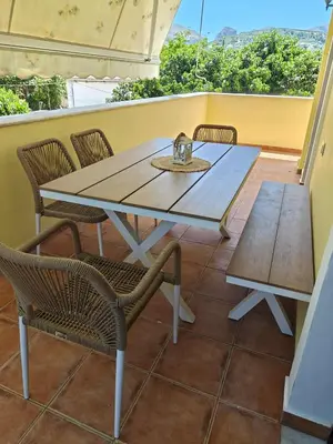 a wooden table and chairs on a balcony with a table and benches at Seaside Escape in Nopíyia