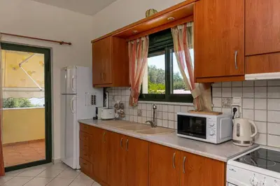 a kitchen with wooden cabinets and a white microwave at Seaside Escape in Nopíyia