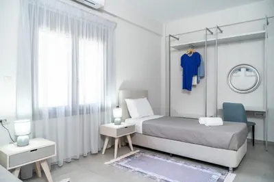 a white bedroom with a bed and a blue shirt on a rack at Villa Emily in countryside in Chania Town