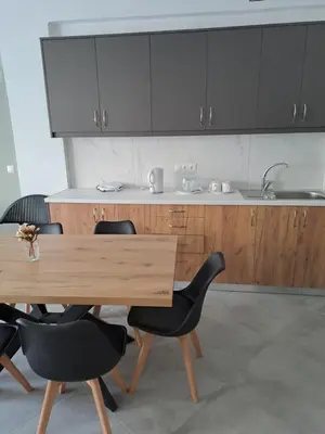 a kitchen with a wooden table and black chairs at Parthenon apartment in Souda
