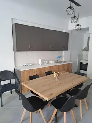 a kitchen with a wooden table and black chairs at Parthenon apartment in Souda