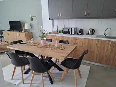 a kitchen with a wooden table and black chairs at Parthenon apartment in Souda