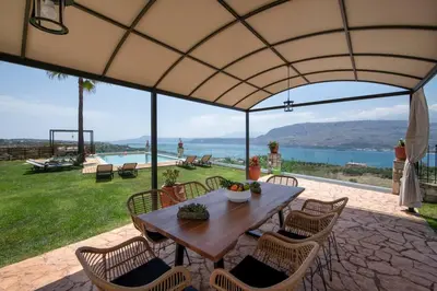 a patio with a table and chairs and a view of the water at Villa Damant in Pithárion