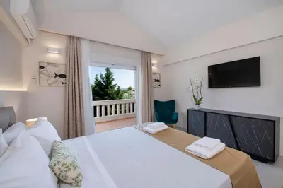 a bedroom with a bed with a television and a balcony at Villa Damant in Pithárion