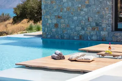 a pool with a table with towels and a bottle of wine at Magical new luxury villa Camellia! in Kissamos