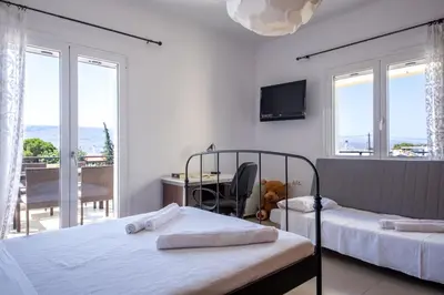 a bedroom with two beds and a desk and windows at Souda Bay View with Private Pool near Chania City in Chania Town