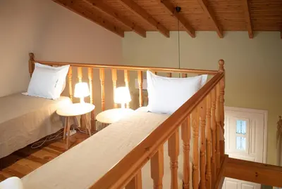 a bedroom with a staircase with a bed and two lamps at glarosmaisonette in Kato Daratso