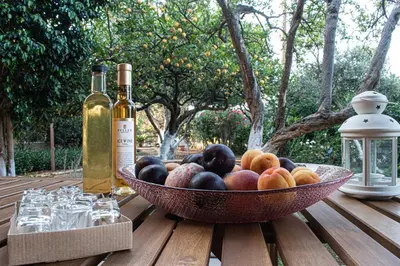 a bowl of fruit on a wooden table with wine bottles at glarosmaisonette in Kato Daratso