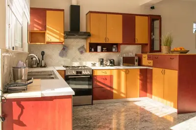a kitchen with yellow and red cabinets and a stove at Searenity Home in Ropanianá