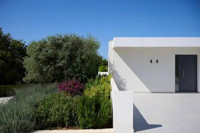a white house with a black door in a garden at Kyamon Luxury Villa with Heated Saltwater Pool Near Chania in Chania Town