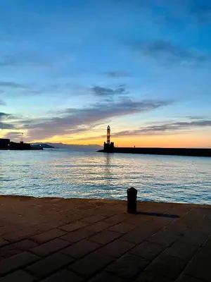 a lighthouse sitting in the water with the sunset at Sea View Apartment #2 in Stalos