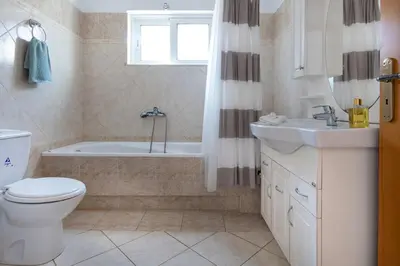 a bathroom with a toilet and a tub and a sink at Iconic Villa with private pool and sea view in Próvarma