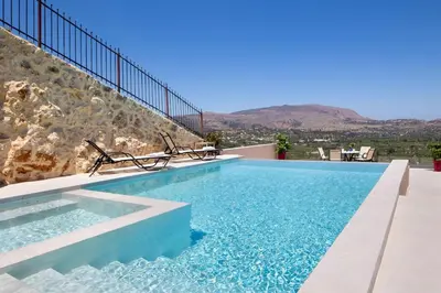 a swimming pool with two chairs on top of a building at Iconic Villa with private pool and sea view in Próvarma