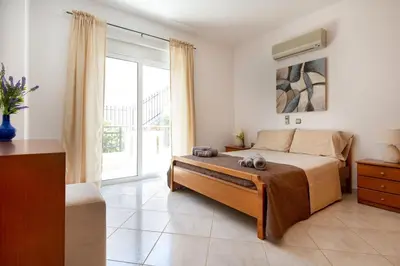 a bedroom with a bed and a large window at Iconic Villa with private pool and sea view in Próvarma