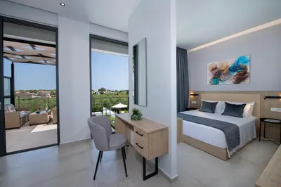 a bedroom with a bed and a desk with a chair at Cretan Queen Residences in Aghii Apostoli