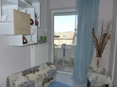 a living room with a chair and a window at Koum Kapi 1st floor apt in Chania Town