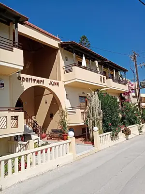a building with a white fence next to a street at John Apartments in Plataniás