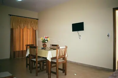 a dining room with a table with chairs and a tv at John Apartments in Plataniás