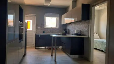 a kitchen with blue cabinets and a table and a bed at Elena Apartments in Kato Daratso
