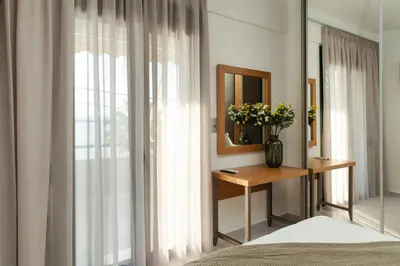a bedroom with a mirror and a table with flowers at Elia Beach Deluxe Apartment in Chania Town