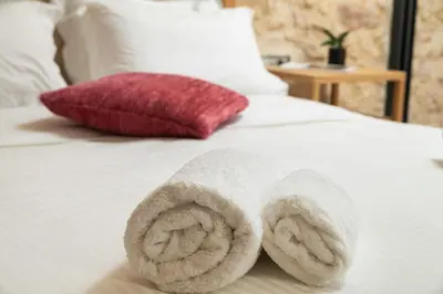 a roll of towels on a bed with a red pillow at The Alma City Suites in Chania Town