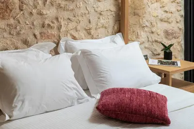 a white bed with white pillows and a table at The Alma City Suites in Chania Town
