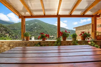a wooden table on a porch with a view of mountains at Maria's House with View in Kambos in Kámbos