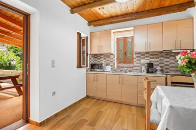a kitchen with wooden cabinets and a table with a table cloth at Maria's House with View in Kambos in Kámbos