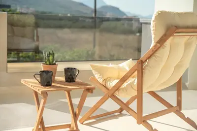 a wooden chair and a side table with a plant at Villenia Luxury Apartments in Kissamos