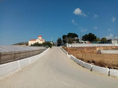 an empty road with a fence and a building in the distance at Vine Veranda in Palaiochóra