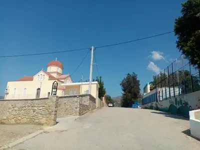 a church on a stone wall next to a street at Vine Veranda in Palaiochóra